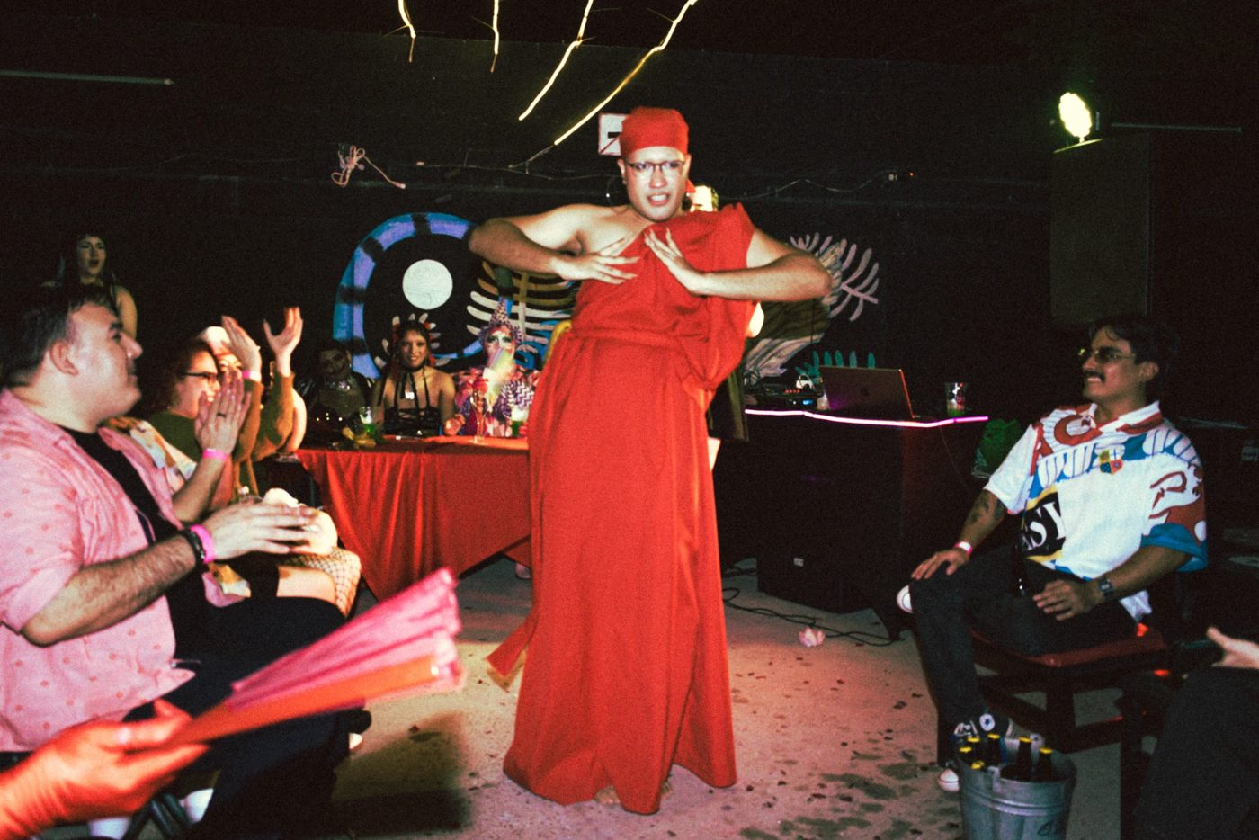 April Cosmic en un ball de House of Cosmic, con vestido rojo, frente al público y los jueces